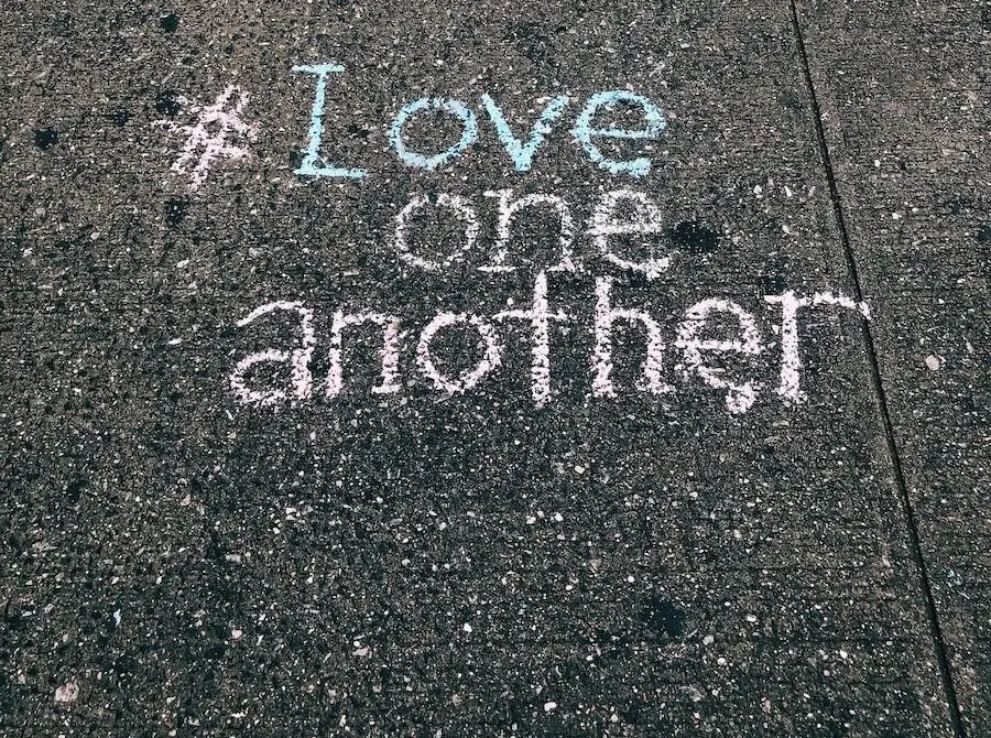 love one another chalk written on concrete floor